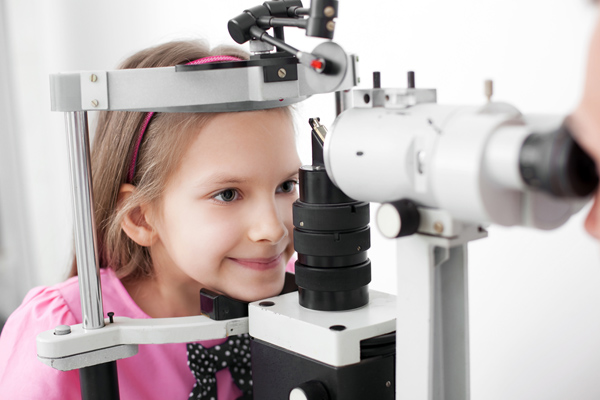 A photo of a young girl using an ophthalmology machine, benefiting from voluntary benefits