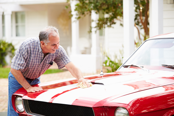 A photo of a man washing his classic car that would benefit from collector car insurance