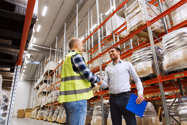 A photo of two workers protected by group life insurance shaking hands in a warehouse