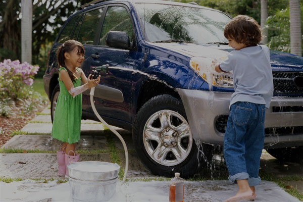 Two kids having fun washing their parents car - Links to Personal Insurance page