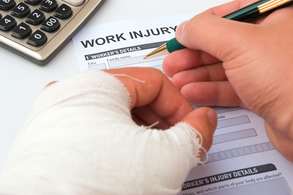 A photo of an employee with arm or hand injury filling out an injury report at work